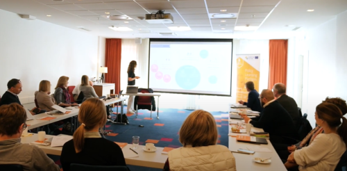forsamling ser opp mot foredragsholder og en powerpoint fremvisning