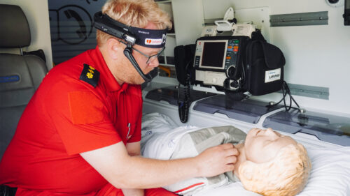mann med sambandsutstyr undersøker pasient inne i en ambulanse