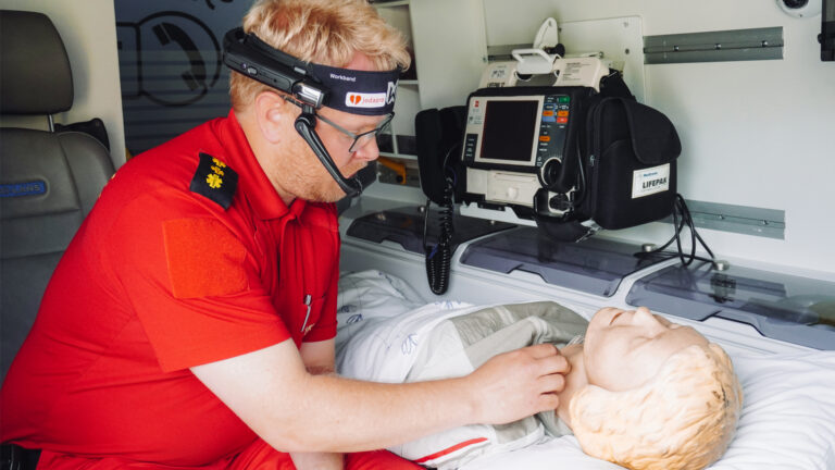 mann med sambandsutstyr undersøker pasient inne i en ambulanse