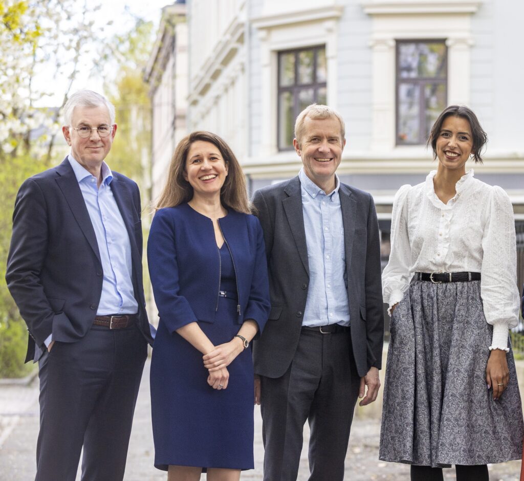 Four people standing outside in front of a building. Two men and two women pose for a photo.